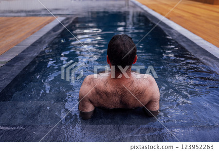 A young attractive man is swimming in an indoor pool. A handsome guy is relaxing 123952263