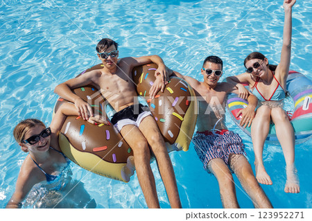 Smiling teenagers in swimsuits and sunglasses swim in the pool. Smiling teenagers in swimsuits and sunglasses swim in the pool. 123952271