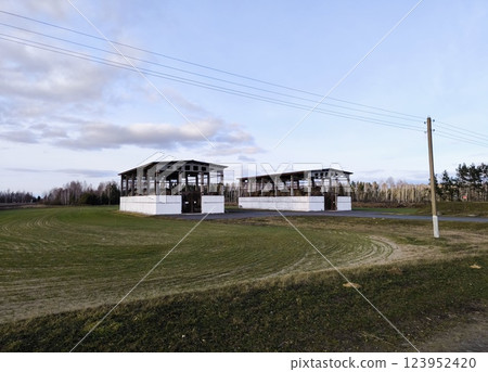 View of Barn and Farm Buildings in Open Field on Sunny Day. Agricultural storage barns in an open field, along the road. 123952420