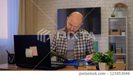 Bald man calculates numbers under soft lamp, focusing on finance tasks while finance goals guide decisions, fueling finance success in personal or business operations. 123953046