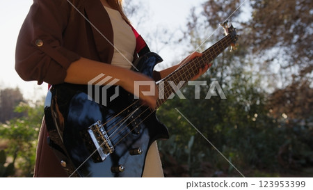 Girl With Sunglasses Plays Bass Musical Instrument In The Countryside Among Tree Girl With Sunglasses Plays Bass Musical Instrument In The Countryside Among Tree 123953399
