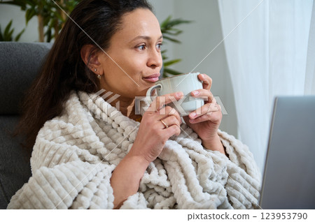 Young Professional Enjoying Remote Work With Warm Beverage in Cozy Home Setting Young Professional Enjoying Remote Work With Warm Beverage in Cozy Home Setting 123953790