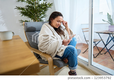 Cozy Remote Work Setup Featuring Young Woman Using Smartphone in Comfortable Home Interior 123953792
