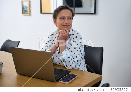 Young Woman Working Remotely at Laptop in Cozy Home Office Setting Young Woman Working Remotely at Laptop in Cozy Home Office Setting 123953812