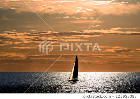 View of a sailing boat at sunset passing in front of the Artruxt Lighthouse, Cuidadela, Menorca, Balearic Islands, Spain	 123955085
