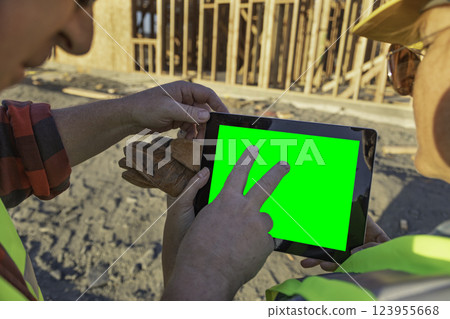 Construction Workers At Construction Site Holding Computer Tablet With Green Screen. Construction Workers At Construction Site Holding Computer Tablet With Green Screen. 123955668