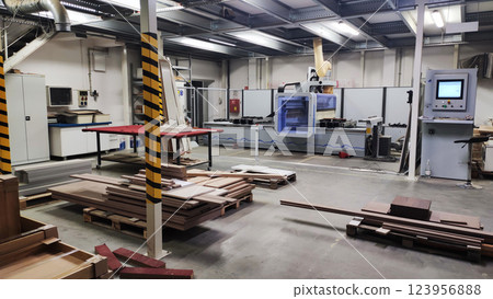 Modern woodworking factory interior with advanced CNC machines, stacked wooden panels, and pallets for furniture manufacturing. High quality photo 123956888