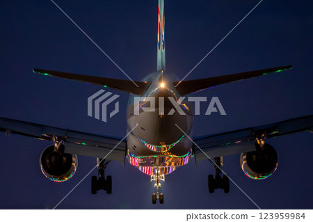 A plane landing with runway lights reflected on its fuselage 123959984