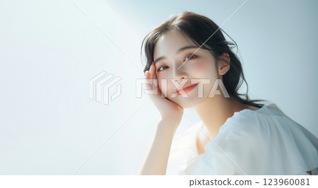A smiling woman is resting her chin on her hand. White background A smiling woman is resting her chin on her hand. White background 123960081