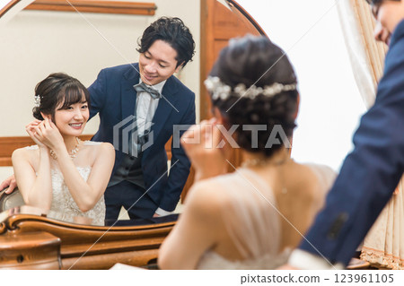 A smiling bride and groom preparing for a wedding ceremony / reception (bridal jewelry / accessories) 123961105