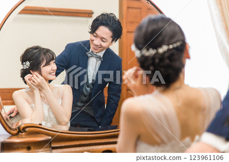 A smiling bride and groom preparing for a wedding ceremony / reception (bridal jewelry / accessories) 123961106