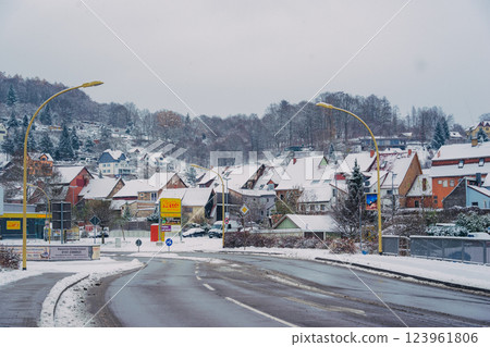 A picturesque snowy road gracefully winding through a charming little village during the magical winter season A picturesque snowy road gracefully winding through a charming little village during the magical winter season 123961806