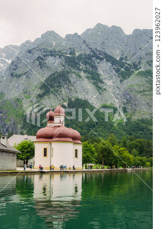 Vintage wooden boathouses line the calm, green waters, surrounded by dense trees and towering mountains under a cloudy sky, creating a tranquil atmosphere in nature. Konigssee lake Bavaria German Alps Vintage wooden boathouses line the calm, green waters, surrounded by dense trees and towering mountains under a cloudy sky, creating a tranquil atmosphere in nature. Konigssee lake Bavaria German Alps 123962027