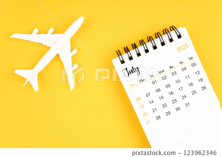 July 2025 calendar and airplane toy on yellow background. 123962346