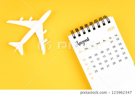 August 2025 calendar and airplane toy on yellow background. 123962347