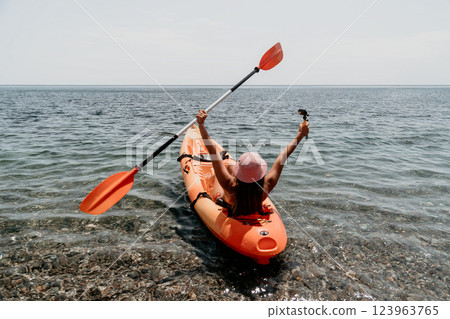 Kayaking Woman Ocean Happy: A woman in a red kayak paddles through the ocean with her arms raised in the air, enjoying a day of kayaking. 123963765