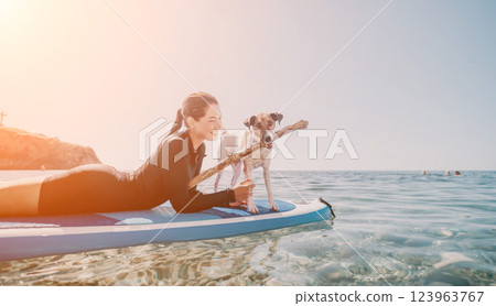 Woman Dog Paddleboard Sunset Ocean - Happy woman paddleboarding with her dog at sunset. Woman Dog Paddleboard Sunset Ocean - Happy woman paddleboarding with her dog at sunset. 123963767