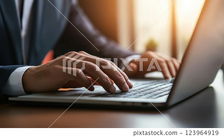 In a contemporary office environment, a dedicated professional is diligently working on a laptop 123964919