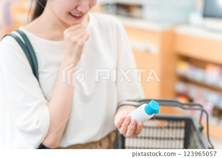 A woman shopping for antiseptic solution, mouthwash, cleaning solution, insect repellent, and over-the-counter medicine at a pharmacy / drugstore 123965057