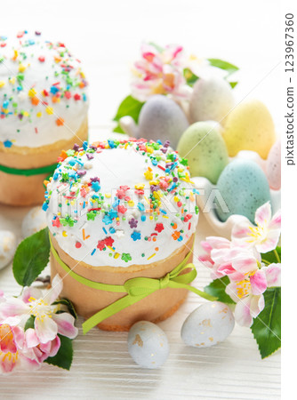 Delicious easter cakes decorated with colorful sprinkles and eggs on white table Delicious easter cakes decorated with colorful sprinkles and eggs on white table 123967360