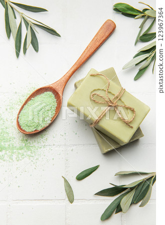 Natural olive soap bars with green bath salt and olive leaves on white tile background Natural olive soap bars with green bath salt and olive leaves on white tile background 123967364