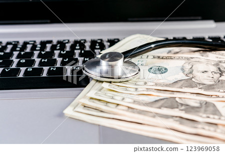 Stethoscope on top of money on laptop keyboard. Stethoscope on dollar bills on top of laptop keyboard Stethoscope on top of money on laptop keyboard. Stethoscope on dollar bills on top of laptop keyboard 123969058