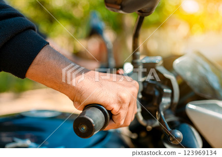 Hands of man on the motorcycle handlebars. Motorbike speeding concept, Hands of a motorcyclist on the handlebars. Close up of the hands on the handlebars of a motorcycle 123969134