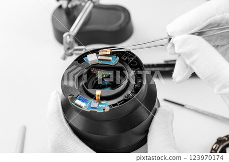 the hands of the master with gloves and a broken lens of a professional camera. the hands of the master with gloves and a broken lens of a professional camera. 123970174
