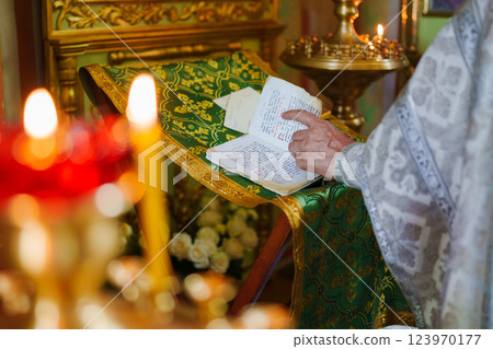 A priest with a prayer book on a table conducts the service.  123970177