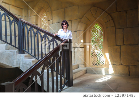 Woman inside arabic style room near massive staircase 123971483