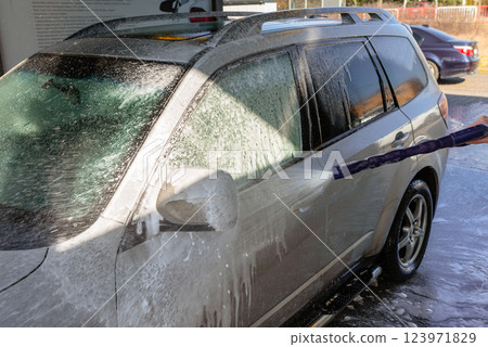 Washing an SUV with high-pressure water and foam at a self-service car wash, cleaning the vehicle exterior on a sunny day 123971829