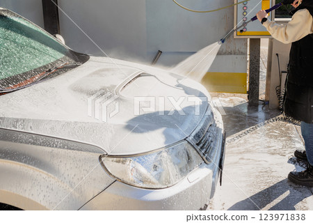 Woman Using High-Pressure Washer to Clean a Dirty SUV at a Self-Service Car Wash Woman Using High-Pressure Washer to Clean a Dirty SUV at a Self-Service Car Wash 123971838
