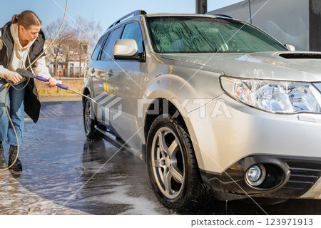 Woman Using High-Pressure Washer to Clean a Dirty SUV at a Self-Service Car Wash Woman Using High-Pressure Washer to Clean a Dirty SUV at a Self-Service Car Wash 123971913
