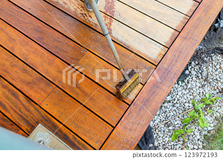 Close-up of a wooden deck being stained with a brush for protection and maintenance 123972193