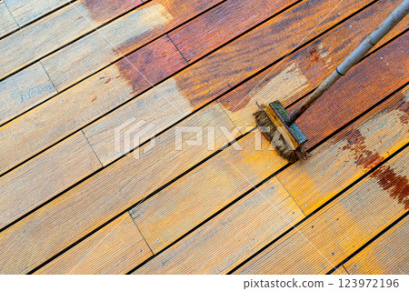 Close-up of a wooden deck being stained with a brush for protection and maintenance 123972196