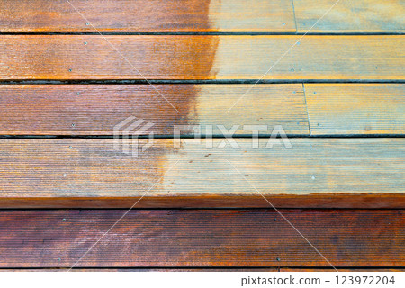 Close-up of a wooden deck showing the process of restoration with a half-stained surface 123972204