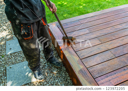 Close-up of a wooden deck being stained with a brush for protection  123972205