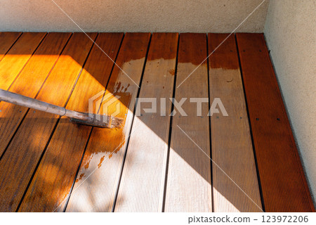 Close-up of a wooden deck being stained with a brush for protection and maintenance 123972206
