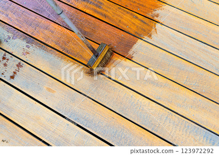 Close-up of a wooden deck being stained with a brush for protection and maintenance 123972292