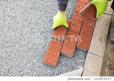Construction worker laying paving stones on gravel for new pavement Construction worker laying paving stones on gravel for new pavement 123972575
