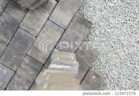 Construction worker laying paving stones and gravel for patio floor Construction worker laying paving stones and gravel for patio floor 123972578