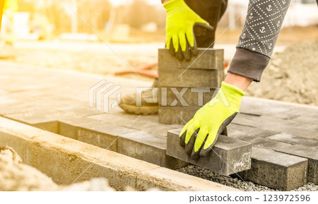Construction worker paving a walkway with concrete or brick pavers Construction worker paving a walkway with concrete or brick pavers 123972596