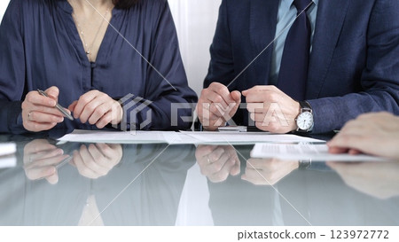 Business partners or lawyers are reviewing contract terms during a meeting, negotiating and making decisions together. Business people concept, close up view Business partners or lawyers are reviewing contract terms during a meeting, negotiating and making decisions together. Business people concept, close up view 123972772