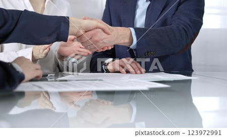 Unrecognizable business partners shaking hands after signing contract at glass table in office meeting, making a deal and closing agreement, close up of handshake Unrecognizable business partners shaking hands after signing contract at glass table in office meeting, making a deal and closing agreement, close up of handshake 123972991