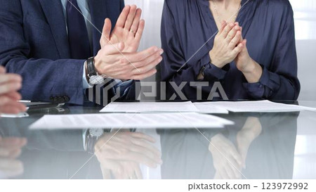 Unrecognizable business professionals applauding and celebrating achievements at glass table after successful meeting and contract signing. Business people concept, close up view Unrecognizable business professionals applauding and celebrating achievements at glass table after successful meeting and contract signing. Business people concept, close up view 123972992
