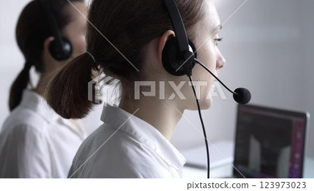 Young female call center operator in white blouse is assisting clients online, providing customer support and answering inquiries. Business call center Young female call center operator in white blouse is assisting clients online, providing customer support and answering inquiries. Business call center 123973023