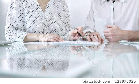 Business colleagues reviewing a contract, engaging in negotiations and strategic decision making in modern glass office, white casual dress style. Businesspeople concept 123973029