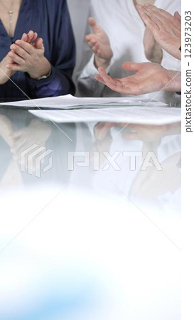Business people or lawyers are applauding and celebrating achievements at glass table after successful meeting, vertical close up view. Concept of success Business people or lawyers are applauding and celebrating achievements at glass table after successful meeting, vertical close up view. Concept of success 123973203