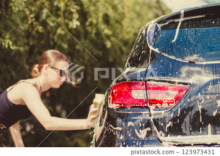 Woman Washing Car with Sponge 123973431