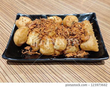Golden Crispy Fried Tofu with Garlic Seasoning on a Black Plate, Wooden Table Background Golden Crispy Fried Tofu with Garlic Seasoning on a Black Plate, Wooden Table Background 123973682